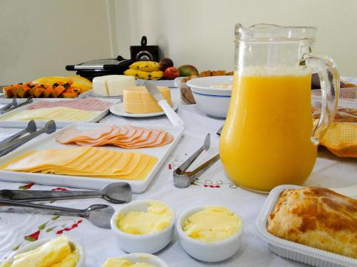 a table with cheese and a jug of orange juice at Pousada Casa do Bosque in Penedo