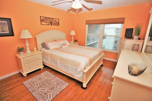 een slaapkamer met een bed met oranje muren en een raam bij Sea Coast Gardens III 514 in New Smyrna Beach