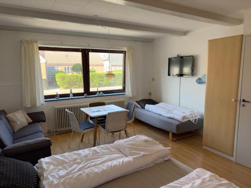 uma sala de estar com uma cama, um sofá e uma mesa em Marskture Hostel em Højer