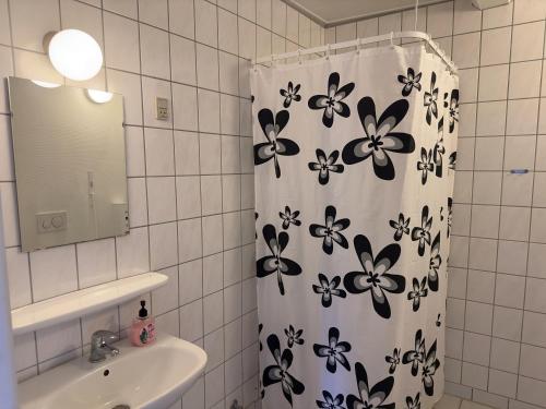 a bathroom with a shower curtain with flowers on it at Marskture Hostel in Højer