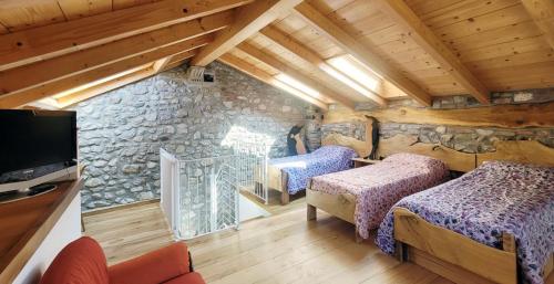 a bedroom with two beds and a stone wall at BALLABIO LAKE - Rustic Chic Retreat in Ballabio