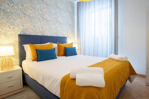a bedroom with a large bed with yellow and blue pillows at Milena's House in Nazaré