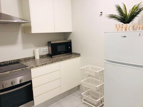 cocina blanca con nevera y microondas en Apartament con Encanto, en Castellón de la Plana