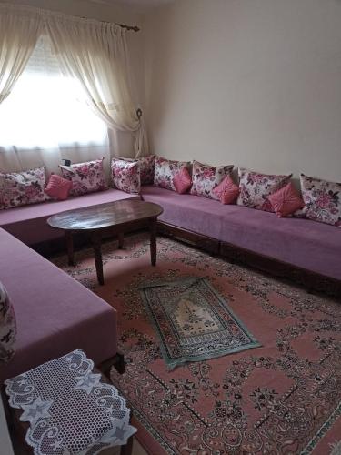 un soggiorno con divano viola e tavolo di Le bon séjour a Ifrane