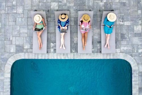 four women in bathing suits are sitting on the towels by a pool at Greyfinch Chatham Inn in Chatham