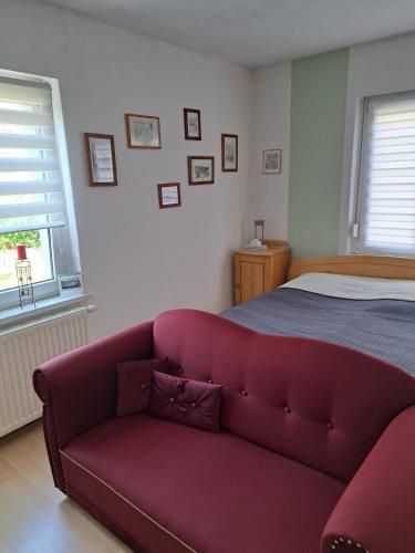 a red couch in a bedroom with a bed at Ferienwohnung Rosengarten in Ballenstedt