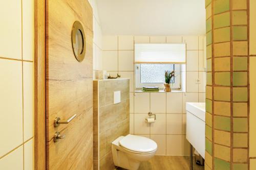 a bathroom with a toilet and a sink and a window at Huus ant Dörpsdiek in Krummhörn