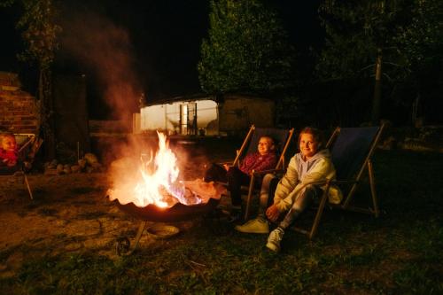 two people sitting in chairs around a fire at Agroturystyka Gorzelnia Gwieździn in Gwieździn