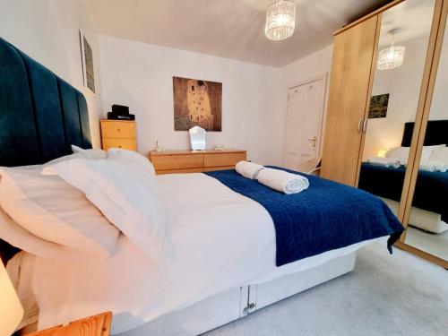 a bedroom with a large white bed and a mirror at Cosy Family Haven: Spacious 3-Bedroom Retreat in Christchurch in Iford