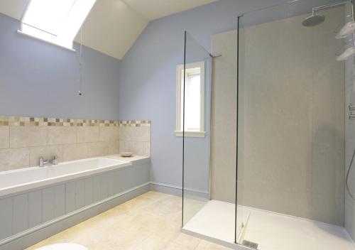 a bathroom with a shower and a tub and a sink at Wing Cottage in Orford