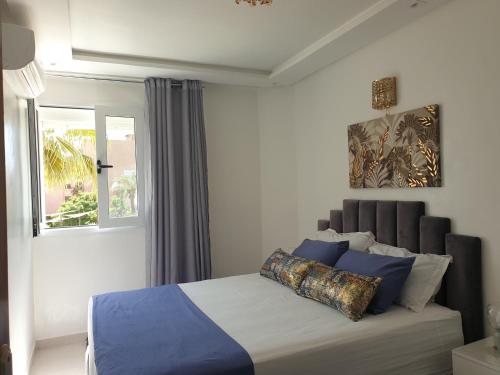 sypialnia z łóżkiem z niebieskimi poduszkami i oknem w obiekcie Bel appartement moderne au cœur de guelize w Marakeszu