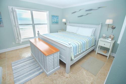 a blue bedroom with a bed and a window at Sea Coast Gardens II 401 in New Smyrna Beach