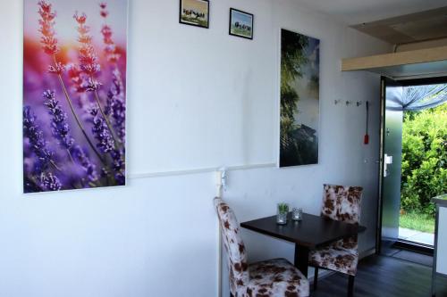 una sala da pranzo con tavolo, sedie e dipinti alle pareti di Tiny Cottage 2 a Drijber