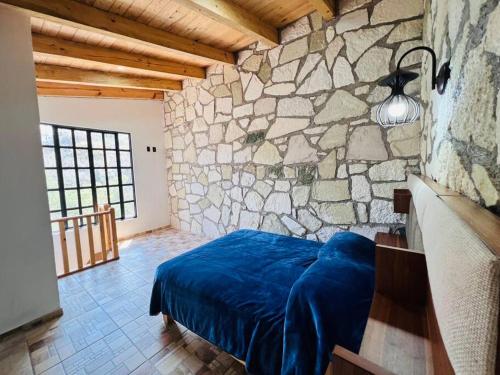 1 dormitorio con 1 cama azul en una pared de piedra en Finca Bermúdez - Cabaña La Uva, en Huasca de Ocampo