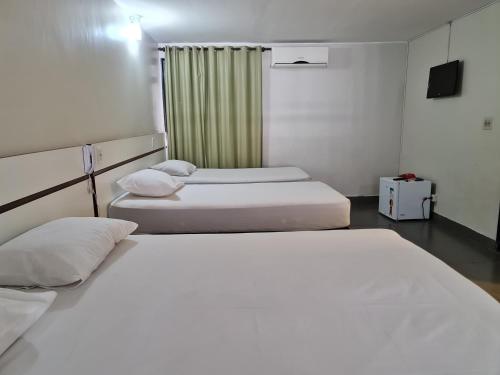 two beds in a room with white sheets at Hotel Montana Aeroporto in Brasilia