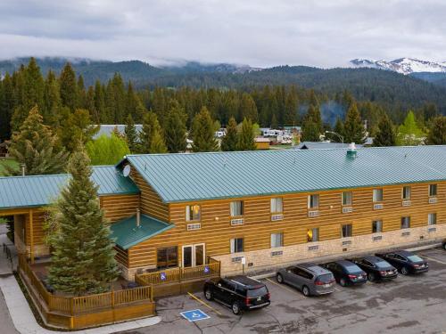 a large log cabin with cars parked in a parking lot at Mountain Vista Hotel in West Yellowstone