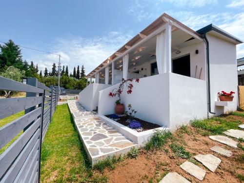 dom z białymi ścianami i płotem w obiekcie Gardy rooms w miejscowości Nea Kallikratia