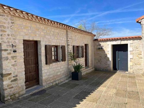 un edificio de ladrillo con 2 puertas y un patio en Gîte aux portes d'Angoulême en Champniers