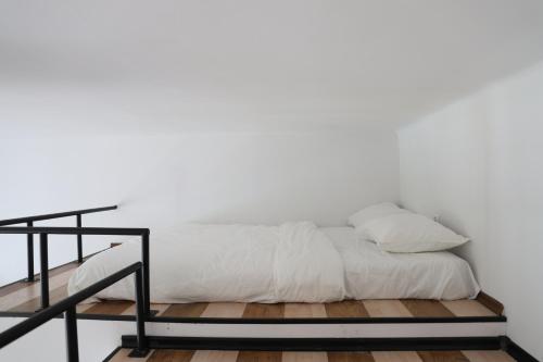 1 cama con sábanas blancas y barandilla negra en Apartament na Placu Wolnica centrum Kazimierza en Cracovia