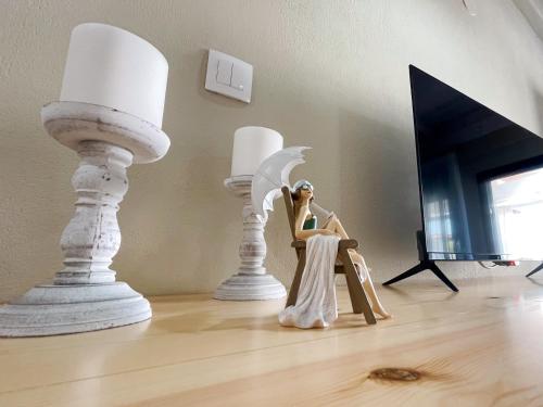 una muñeca sentada en el suelo junto a dos estatuas blancas en Gardy rooms, en Nea Kalikratia