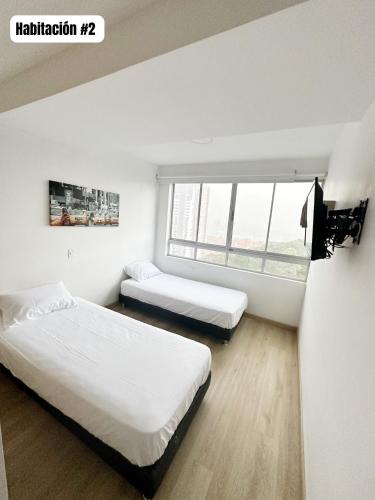two beds in a room with a window at Hermoso y Lujoso Apartamento en Sabaneta in Sabaneta