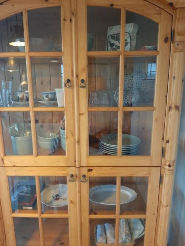 a wooden cabinet with glass doors filled with dishes at Guesthouse Holmur in Hólmur