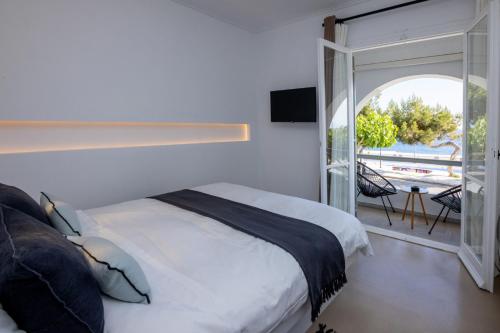 um quarto com uma cama e uma porta de vidro deslizante em SEAMENTO suites em Tinos