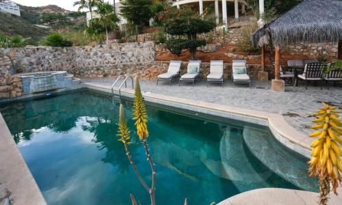 a swimming pool with chairs next to a stone wall at Casa Flamingo Cabo Luxurious Home, Spacious Rooms in El Pedregal Gated Community in Cabo San Lucas