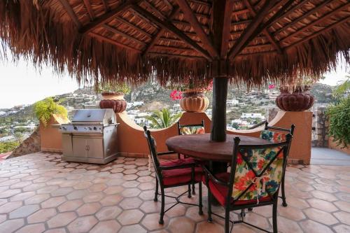 a table and chairs under an umbrella on a patio at Casa Flamingo Cabo Luxurious Home, Spacious Rooms in El Pedregal Gated Community in Cabo San Lucas