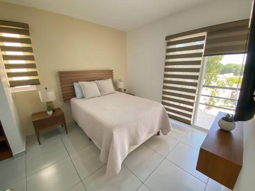 a white bedroom with a bed and a window at Frida's Rooftop in Puerto Morelos
