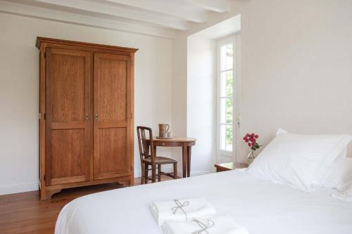 une chambre avec un lit blanc et une armoire en bois dans l'établissement Maison Gamboia, chambres d'hôtes au calme avec jardin, à Hasparren