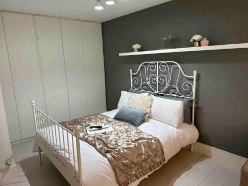 een slaapkamer met een bed met een grijze muur bij Chetwynd Paradise in Londen