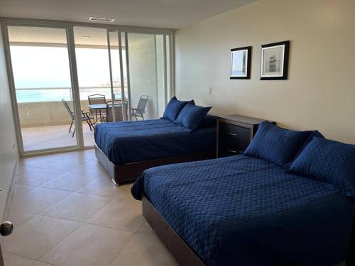 a hotel room with two beds and a balcony at Calafia, Oceanview Condo Resort in Rosarito. in Rosarito