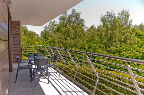 a balcony with a table and chairs and trees at BlueApart Apartamenty Na Klifie in Władysławowo