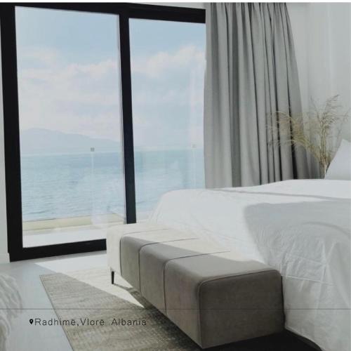 a bedroom with a white bed and a large window at Swiss Rivage Hotel in Vlorë