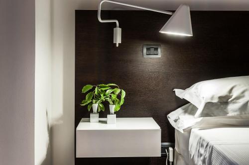 a nightstand with a plant on it next to a bed at Ramo d'Aria Etna Boutique Hotel in Giarre