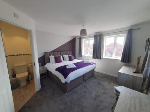 a bedroom with a bed with purple sheets and windows at Bristol House By Cliftonvalley Apartments in Bristol