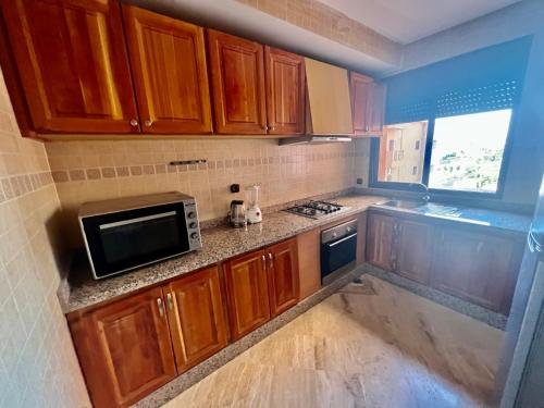 una pequeña cocina con armarios de madera y microondas en Appartement les résidences du rêve en Marrakech