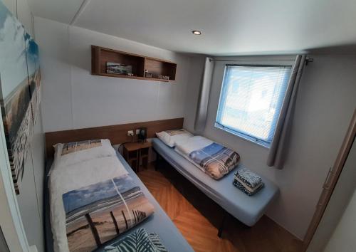 a small room with a bed and a window at Chalet DIE SONNE in Oostkapelle