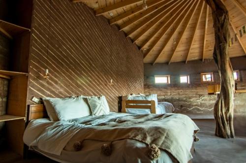 a bed in a room with a wooden ceiling at Vernacular Lodge in San Pedro de Atacama