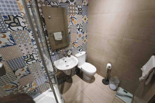 een badkamer met een toilet, een wastafel en een spiegel bij Olivias in Qormi