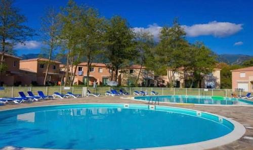- une grande piscine avec des chaises bleues dans la cour dans l'établissement Studio résidence les Villas de Melody, à Moriani-Plage