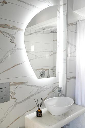ein Badezimmer mit einem weißen Waschbecken und einem Spiegel in der Unterkunft Villa Maina in Kamari