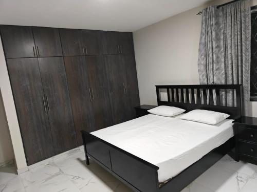 a bedroom with a large bed and wooden cabinets at Amazing Studio near CBD in Mombasa