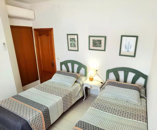 a room with two beds and a table with a lamp at Hostal Noray in Sant Feliu de Guixols