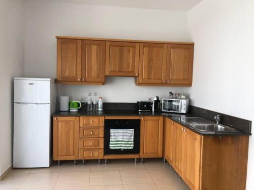 uma cozinha com armários de madeira e um frigorífico branco em Tigne 3 Sliema one bedroom apartment em Sliema