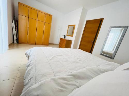 um quarto com uma grande cama branca e uma porta de madeira em Tigne 3 Sliema one bedroom apartment em Sliema