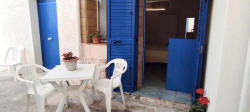 a white table and chairs in front of a blue door at Punta San Simone in Marettimo