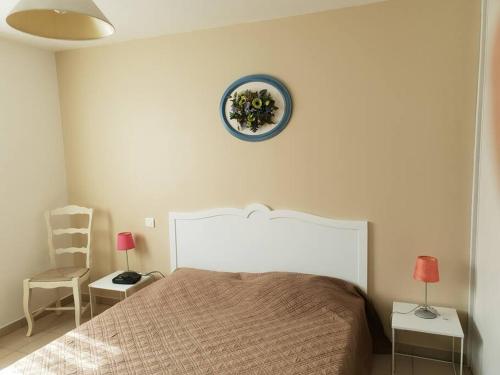a bedroom with a bed and a blue clock on the wall at MAISON avec 1 CHAMBRE dans QUARTIER RESIDENTIEL VERDOYANT CALME in Vendays-Montalivet