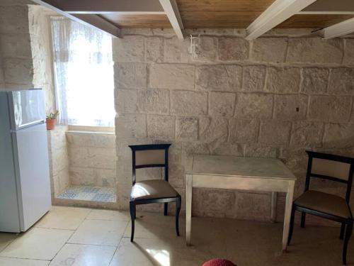 a table and two chairs in a room with a stone wall at Serenity 2 in Qormi